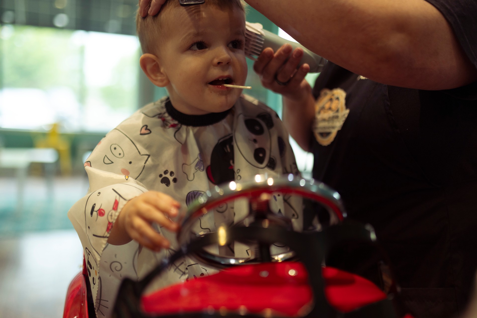 Un mignon garçon se fait couper les cheveux et mange une sucette